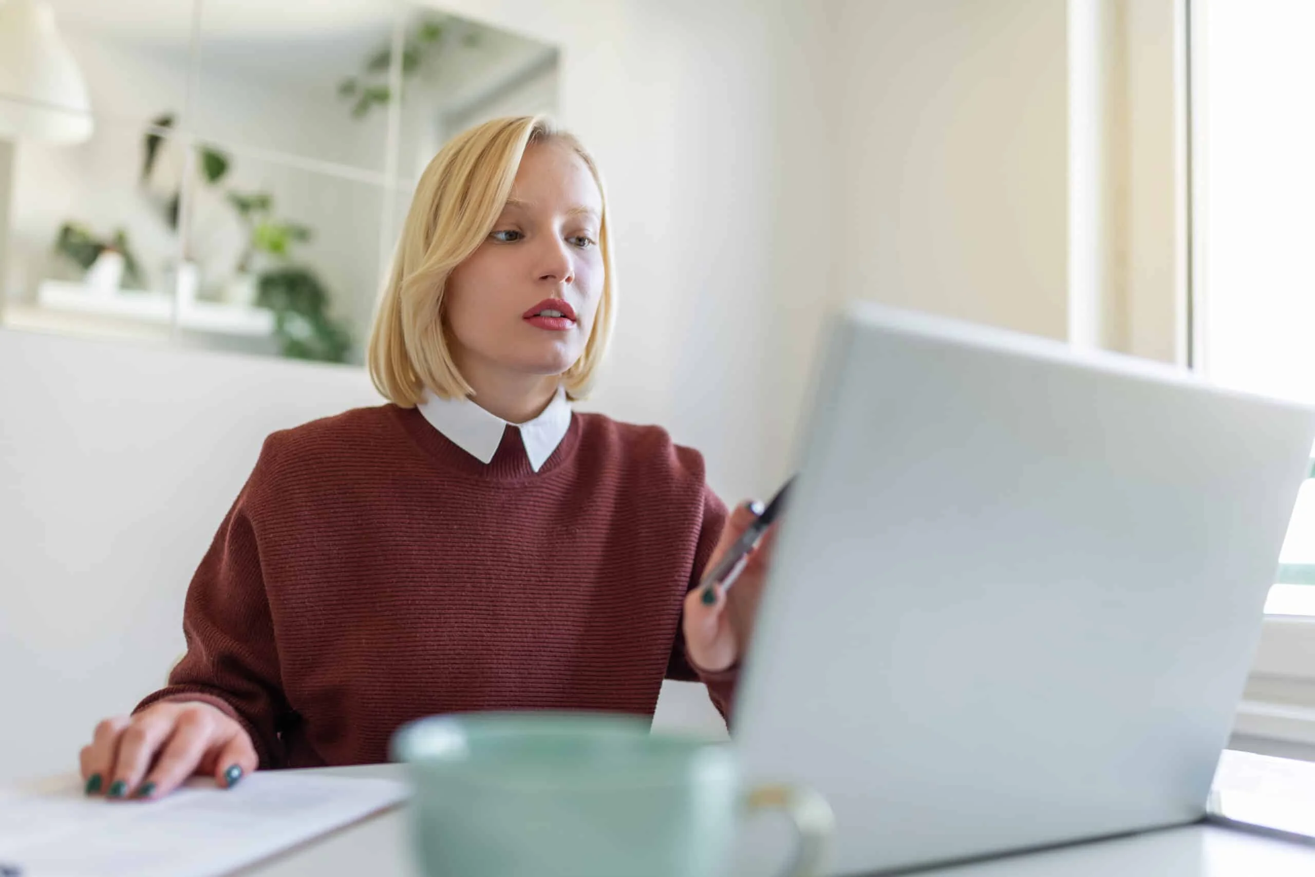A young woman works remotely on a laptop in her apartment.