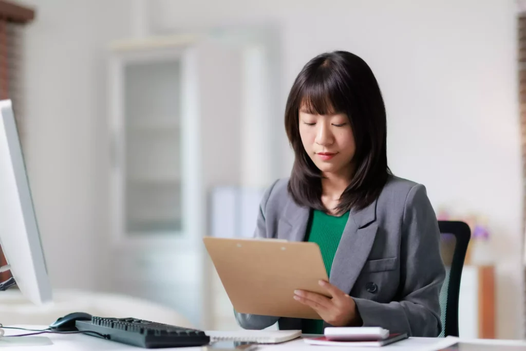 Business professional reviewing reports and notes at an office workstation