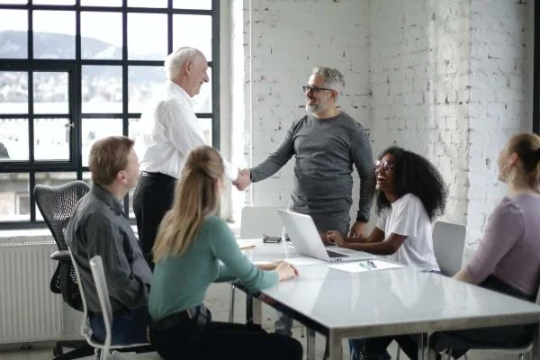cheerful colleagues shaking hands during meeting in modern room