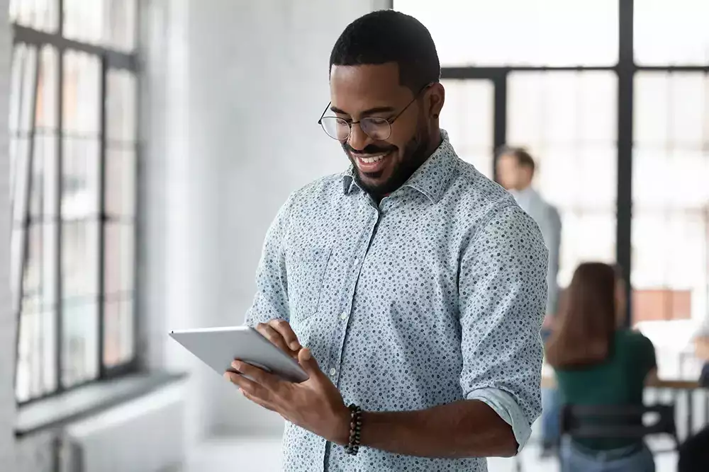 young african american man smiling and reading a tablet
